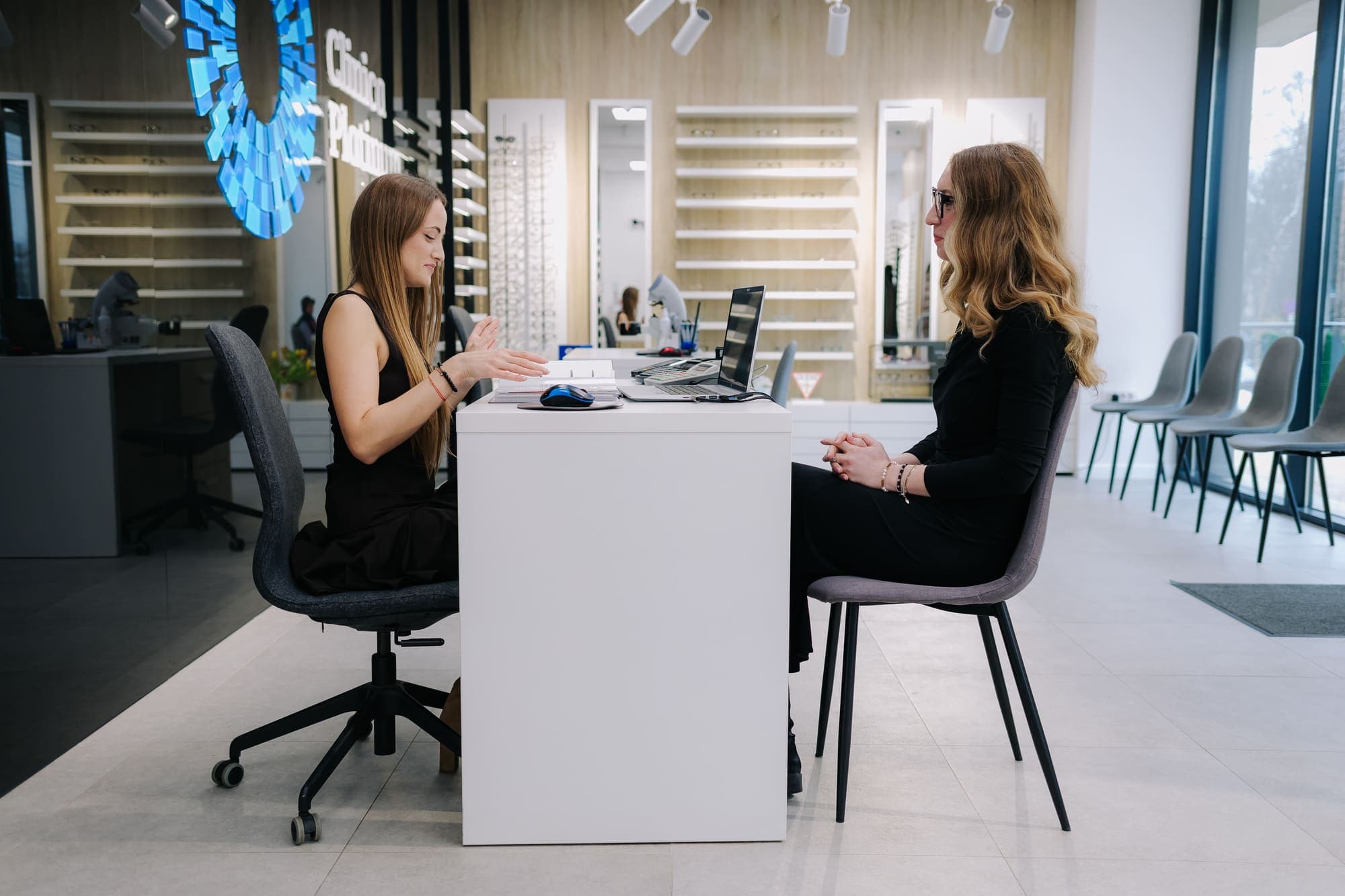 Consilier Platinum Optic discutând opțiunile de ochelari cu o clientă, la biroul de consiliere